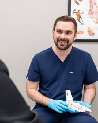 An Evolve Health podiatrist holding a foot model while talking with a patient