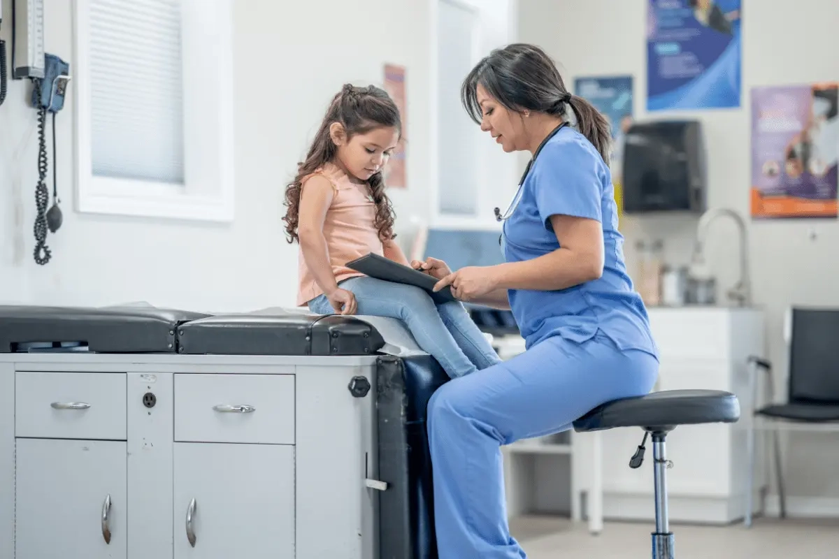 Podiatrist in blue scrubs examining a child’s foot in a clinical setting, illustrating pediatric foot health evaluation