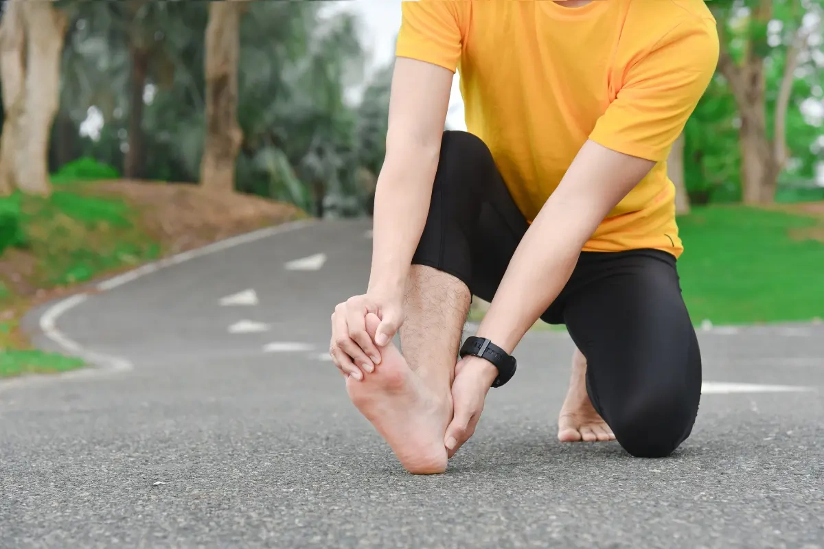 Runner holding foot with inner arch pain after exercise