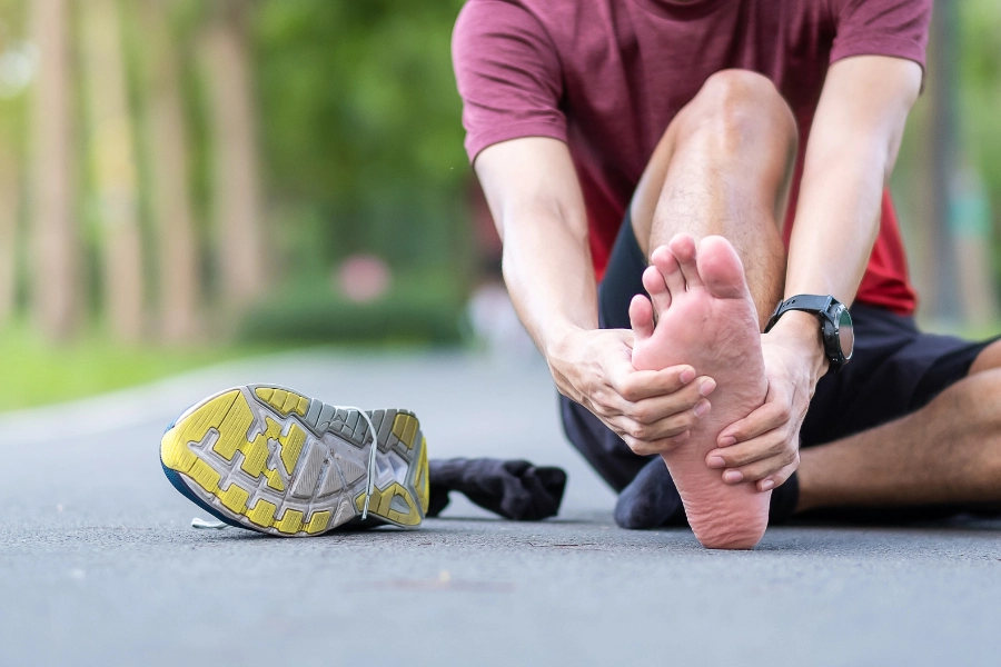 runner holding sore heel after wearing shoes, example of plantar fasciitis discomfort