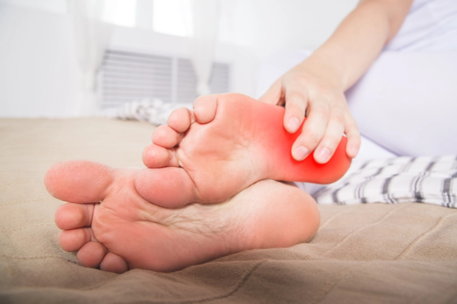 Person holding their foot with morning heel pain from plantar fasciitis, treated by Evolve Health podiatrists.