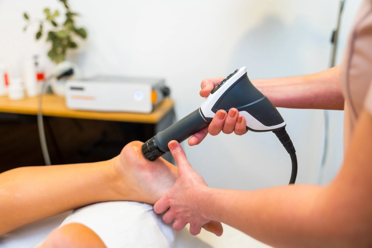 Specialist applying shockwave therapy for foot pain to patient’s heel area.