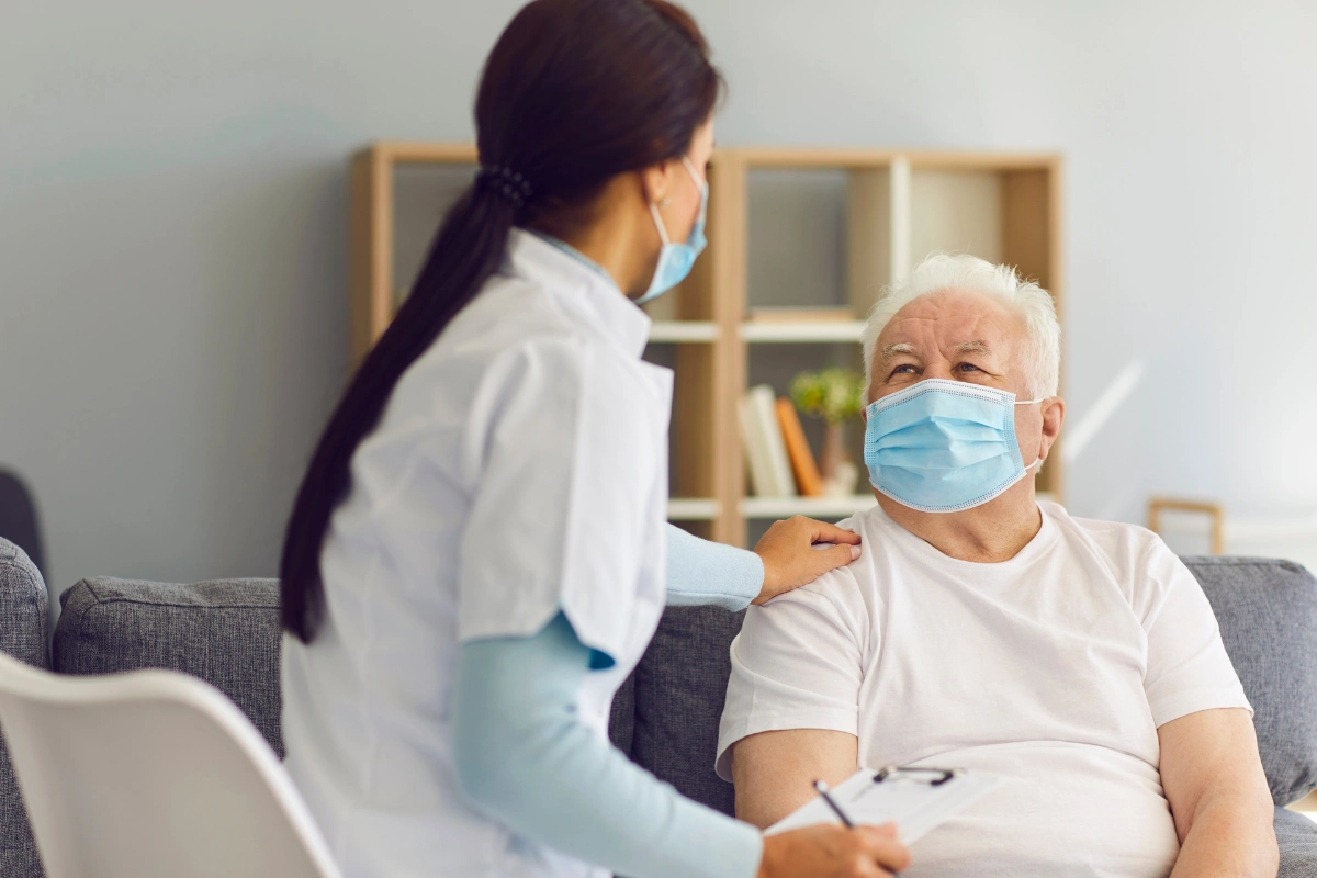 Nurse conducting fall risk assessment for older adult patient wearing a mask